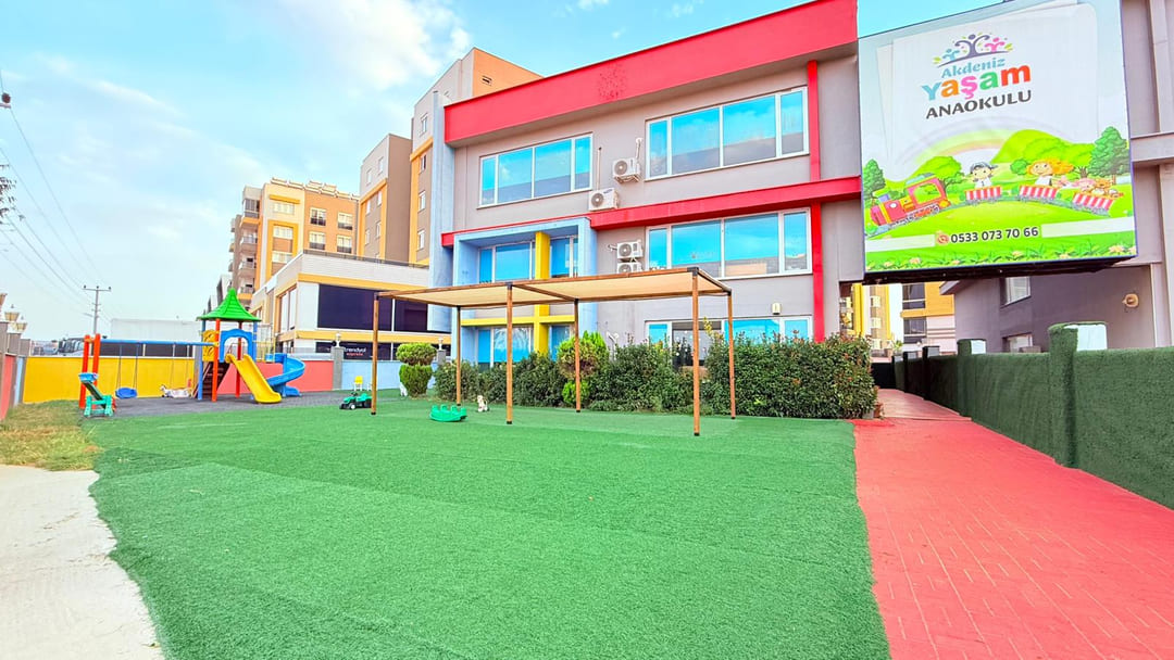 Anaokulu çim kaplı oyun bahçesi ve bina
